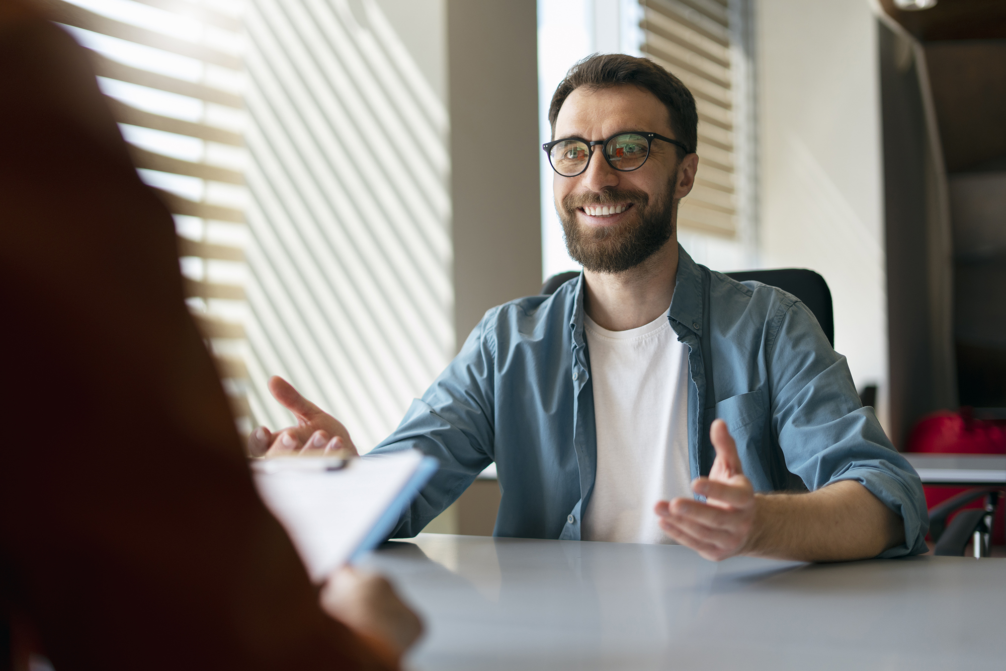 Confident smiling man wearing eyeglasses sitting at job interview.